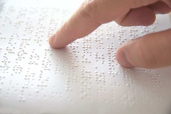 Fragment dłoni osoby czytającej dokument w alfabecie Braille'a