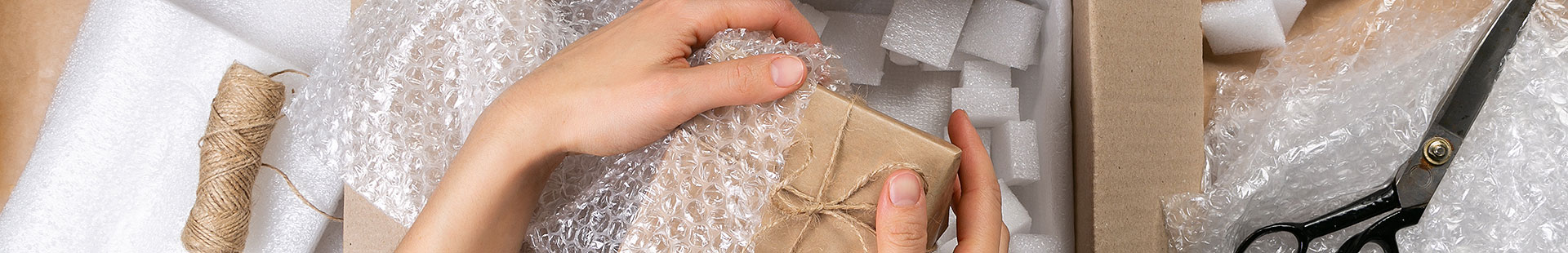 Hands, packing packet in bubble wrap
