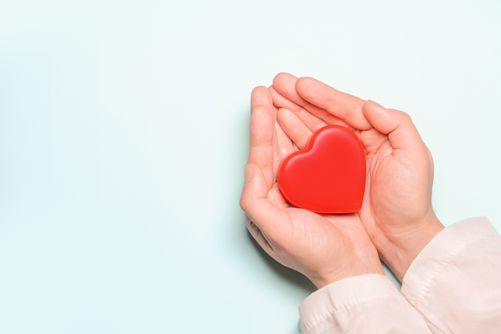 złożone dłonie trzymające czerwone serce