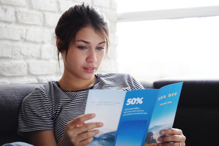 young woman reading an advertising leaflet
